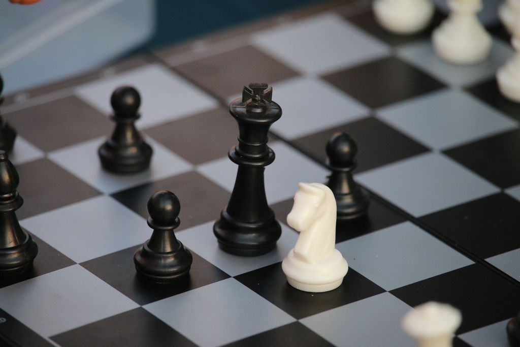 Close-up of a chessboard with black and white pieces in strategic positions.